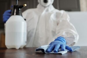 Persona con equipo de protección desinfectando una superficie