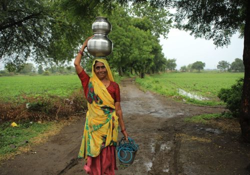 Mujer transportando agua en una zona rural sin saneamiento