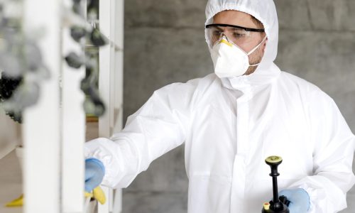 man-with-suit-disinfecting-shelf