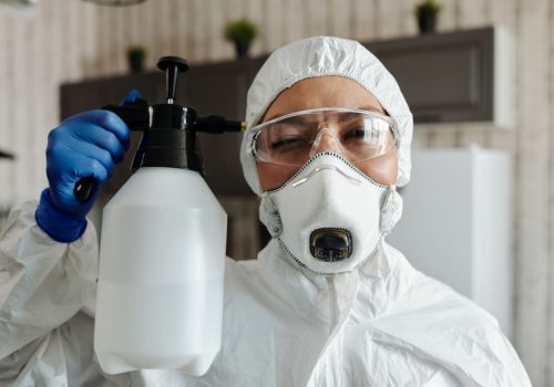 Técnica con equipo de protección aplicando un producto biocida en interiores